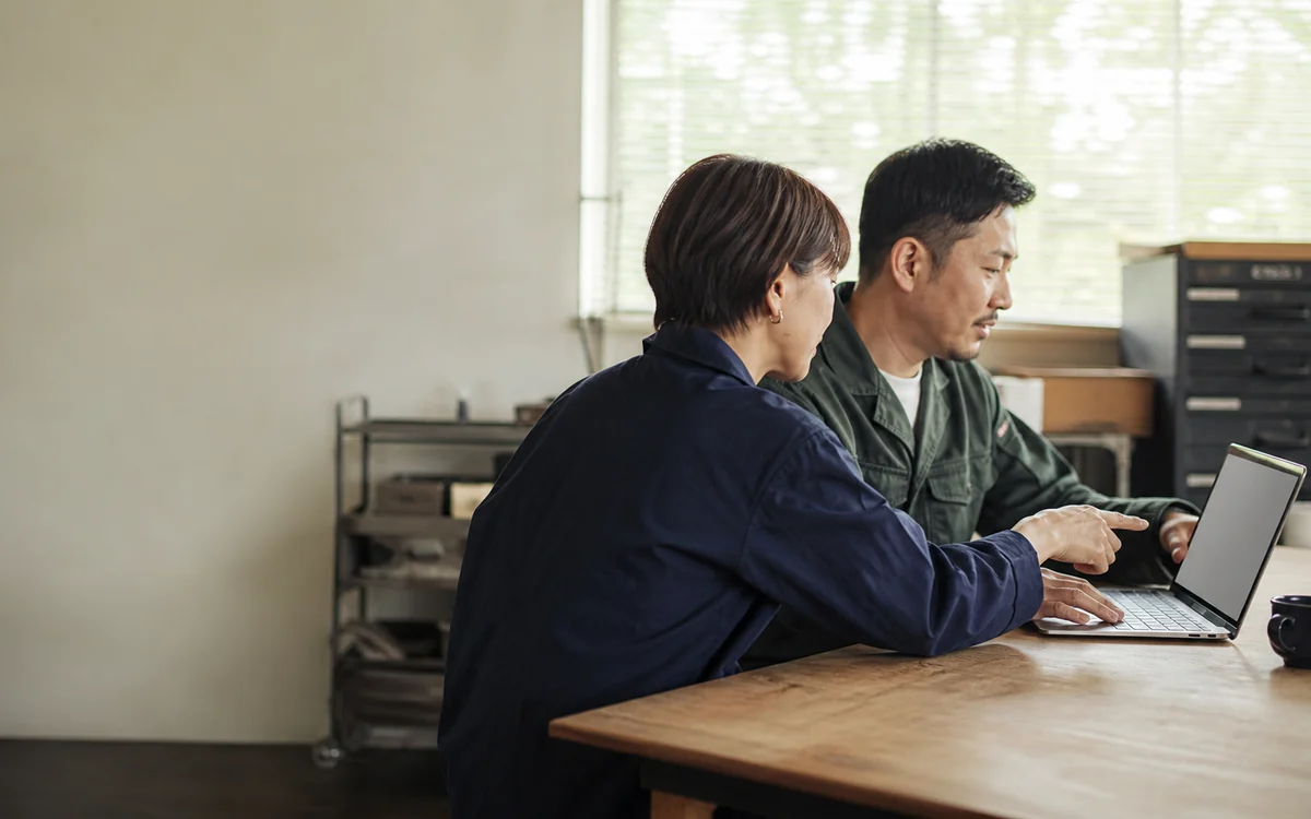一台のノートPCを見ながら業務を確認する二人